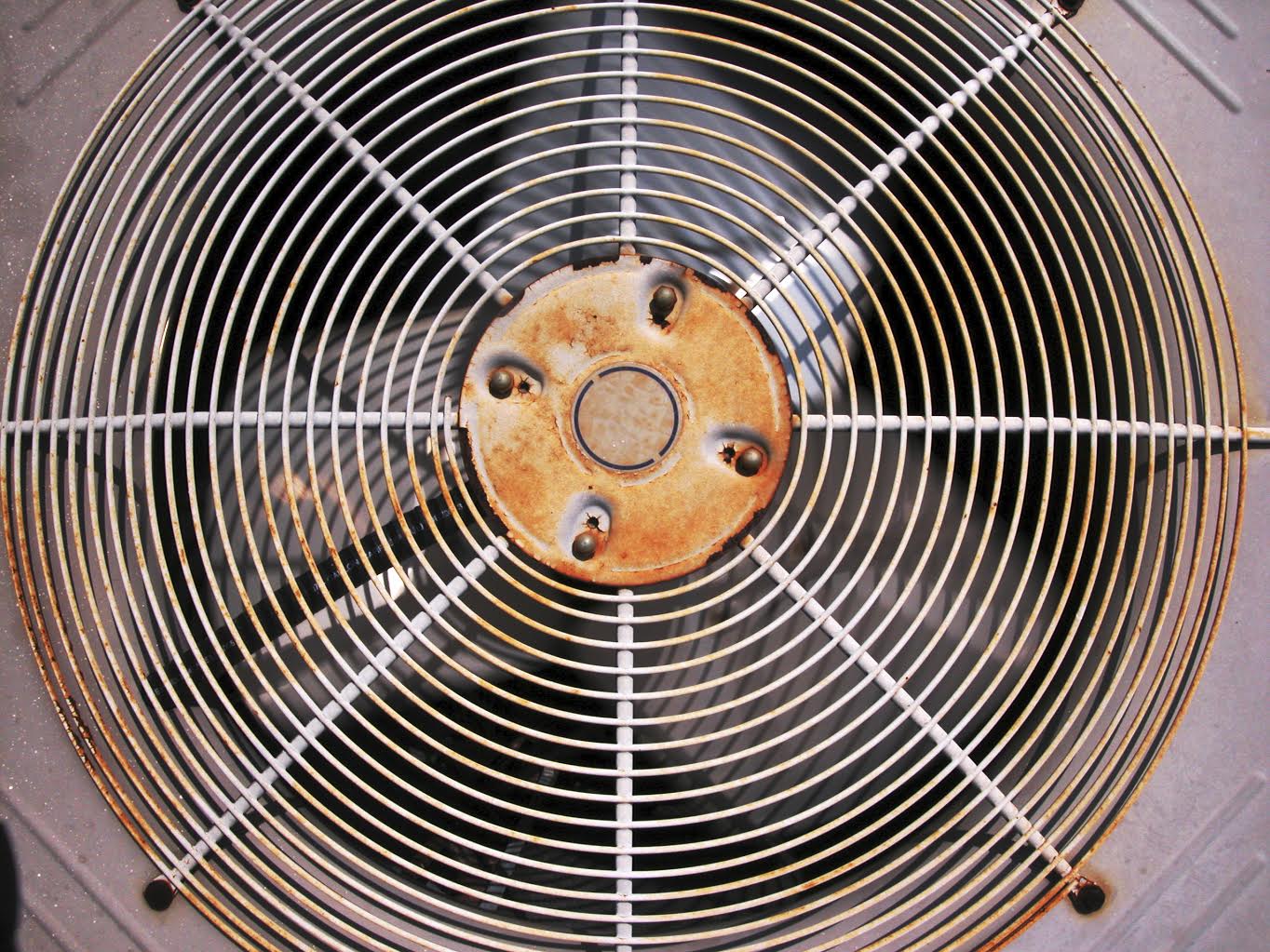 rusty and old air conditioner fan grill located in the back of house